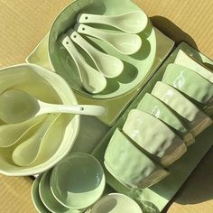 green dishes and spoons are laid out on a cardboard box with white utensils