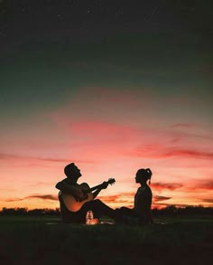 a man and woman sitting on the ground playing guitar at sunset with stars in the sky