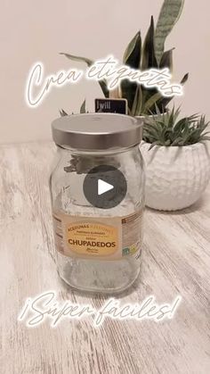 a jar filled with water sitting on top of a wooden table next to a potted plant