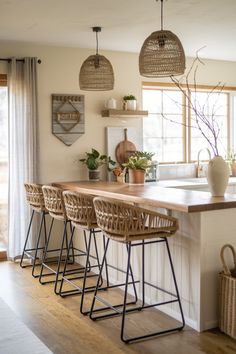 a kitchen island with four stools in front of it and plants on the counter