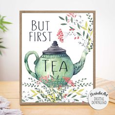 a green teapot with the words but first on it, surrounded by greenery and berries