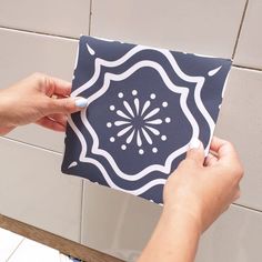 a person is using a marker to draw on a tile