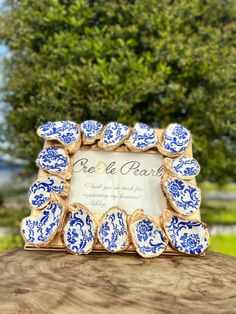 a blue and white plate with an ornate frame is on top of a tree stump