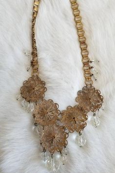 "This is a vintage 1920s-1930s statement necklace. The gold tone metalwork is very intricate and is in a round filigree design. There is one visible area of tarnish (pictured) from wear and age. The necklace has a unique chain and crystal tone details. All of the crystal tone gems are in excellent condition. Overall this necklace is in great condition. Measurements: Length: 9.5\" | Length of detail: 2.5\" Unless otherwise stated all vintage items are used and may have minor to moderate wear or d Vintage Gold Round Bridal Necklace, Vintage Metal Jewelry With Intricate Design, Vintage Antique Gold Decorative Jewelry, Bronze Filigree Jewelry For Vintage Collection, Vintage Bronze Filigree Jewelry, Ornate Gold-tone Metal Jewelry, Vintage Filigree Round Necklaces, Ornate Metal Jewelry For Vintage Collection, Ornate Metal Jewelry Vintage Collection