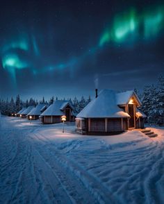 the aurora lights shine brightly in the night sky over snow - covered houses and trees