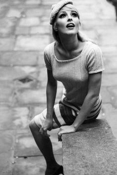 a black and white photo of a woman sitting on top of a suitcase with her mouth open