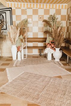 there are plants and vases on the floor in front of a checkered wall