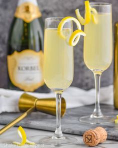 two champagne flutes with lemon wedges on the rim