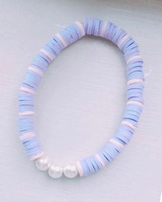 a blue and white beaded bracelet with two pearls on the end, sitting on a table