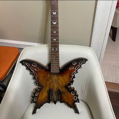 a butterfly shaped guitar sitting on top of a white chair