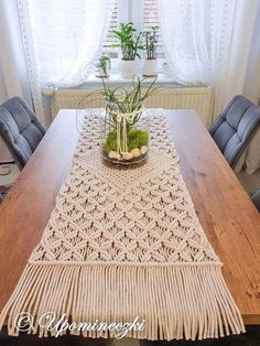 a wooden table topped with a potted plant and a white crochet runner