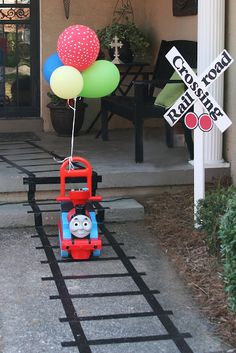 a thomas the tank engine train with balloons attached to it's front door,