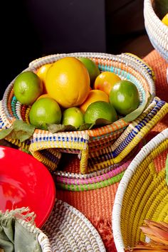 two baskets filled with lemons and limes on top of a cloth covered table