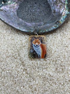 a necklace with a red fox on it sitting in front of a bowl filled with rice