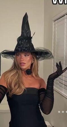 a woman wearing a witches hat and black gloves