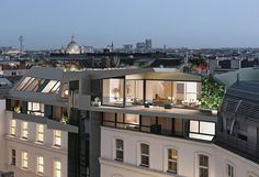 an apartment building is lit up at night with the city in the background and lights on