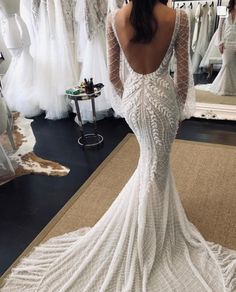 a woman in a white wedding dress looking at her reflection in the mirror while she is standing