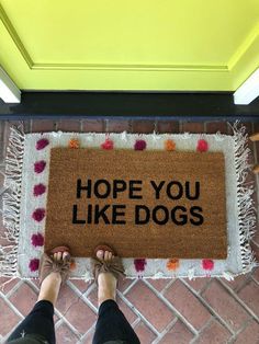 a person standing in front of a door mat that says, hope you like dogs