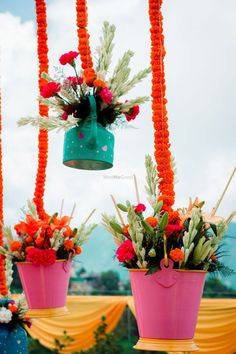 three buckets with flowers hanging from them are suspended in the air by orange string