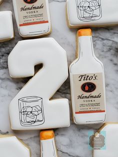 decorated cookies are arranged in the shape of numbers with bottles and glasses around them on a marble surface