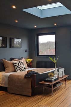 a bed sitting in the middle of a living room next to a window on top of a hard wood floor