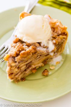 a piece of pie on a green plate with ice cream and fork next to it