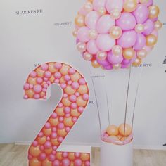 the number two is decorated with balloons in pink, orange and yellow colors on display