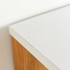 a close up view of a white counter top with wood grain on the edge and bottom