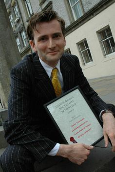 a man in a suit and tie holding an award