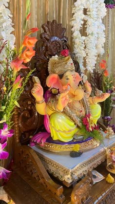 there is a statue of an elephant with flowers in the back ground and other decorations around it