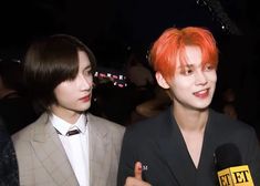 two young men standing next to each other in front of microphones and one wearing a suit