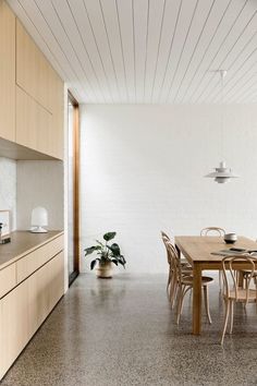 a dining room table and chairs in front of a white wall with wood paneling