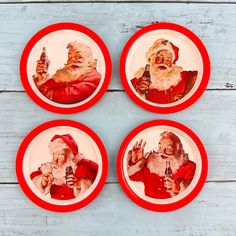 four plates with santa claus on them are sitting on a table and one has a beer in his hand