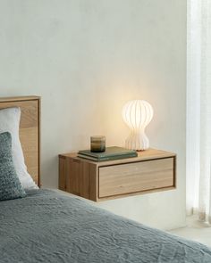 a bed sitting next to a night stand with a lamp on it's side