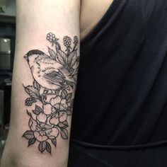 a bird sitting on top of a branch with flowers