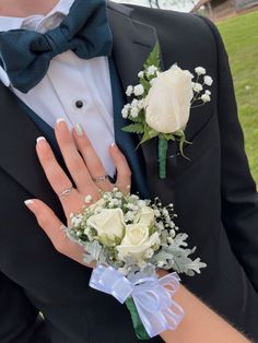 a close up of a person wearing a suit and tie with flowers on his lapel