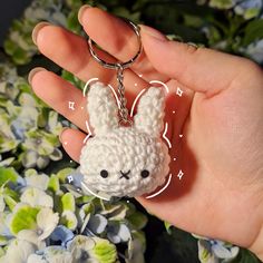 a hand holding a tiny crocheted keychain with a bunny face on it