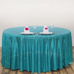 two plates with cake on them are sitting on a round table covered in teal sequins