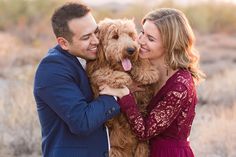 a man and woman are holding a dog in their arms as they smile at each other