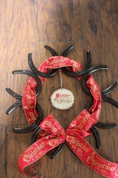 a christmas wreath made out of horseshoes and ribbon on a wooden floor with merry christmas message