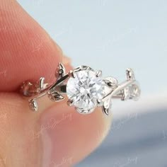 a close up of a person's hand holding a ring with a diamond in it