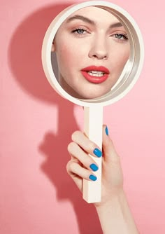 a woman's hand holding a mirror over her face