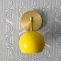 a yellow light is hanging on the wall next to a blue and white striped wallpaper