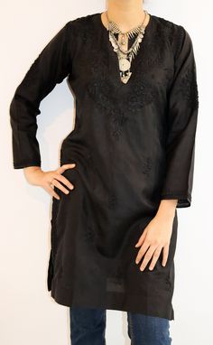 Step into a realm of timeless allure with our Kiara Pure Silk Chikankari Tunic in lustrous black, adorned with resplendent self-embroidery crafted in vintage chikankari stitches.  This exquisite piece is a symphony of tradition and sophistication, showcasing the artistry of skilled hands. The tunic boasts a chic split neck, adding a touch of allure to its classic silhouette, while side slits ensure comfort and ease of movement.  Immerse yourself in the luxury of pure silk and the rich heritage of chikankari, and let this captivating tunic become a statement of elegance in your wardrobe. Revel in the sheer beauty of tradition and modernity gracefully entwined. Full Sleeves.  Length - 36 inches Sizes - S - fits bust 34 M - fits bust 36 L - fits bust 38 XL - fits bust 40 0X - fits bust 42 1X Elegant Kurta With Embroidered Neckline For Festivals, Black Bohemian Kurta With Intricate Embroidery, Elegant Black Kurta With Resham Embroidery, Formal Black Kurta With Floral Embroidery, Transitional Black Kurta With Floral Embroidery, Traditional Black Silk Kurta, Black Fitted Silk Kurta, Black Chikankari Embroidery Kurta For Transitional Season, Elegant Black Kurta With Intricate Embroidery