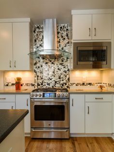 a kitchen with white cabinets, stainless steel appliances and wood flooring is seen in this image