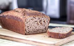 a loaf of bread sitting on top of a cutting board next to a slice of bread