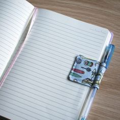 an open notebook with a notepad and pen attached to the cover, sitting on a wooden table