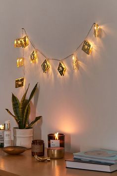 a wooden table topped with a potted plant next to a candle and some books