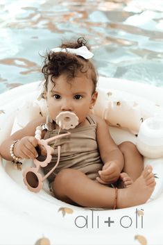 a baby is sitting in an inflatable pool with scissors and hair combs