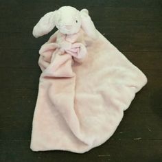 a stuffed rabbit is wrapped in a pink blanket on the floor with its eyes closed